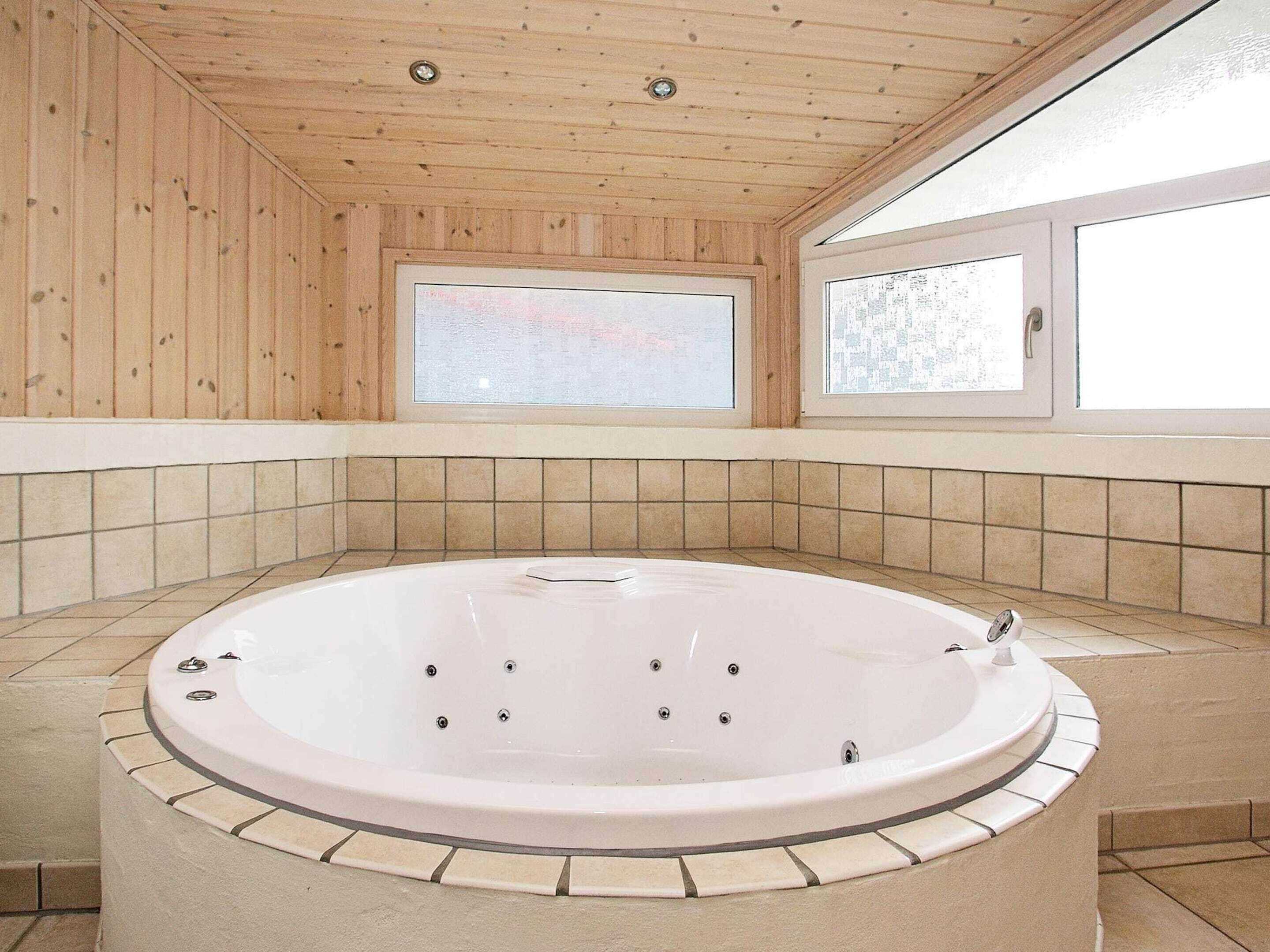 Une salle de spa dotée d’une grande baignoire, de murs en bois et d’une vue par la fenêtre.