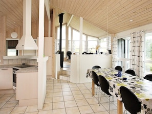 A modern kitchen with a central island, a dining area with a table and chairs, and large windows providing natural light.