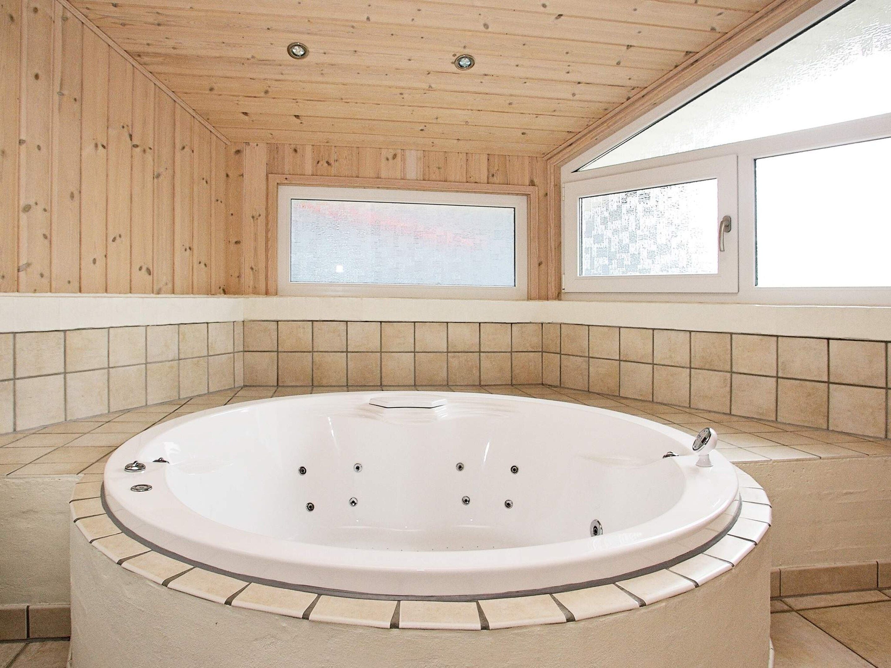 Ett spa-rum med ett stort badkar, träväggar och ett fönster.