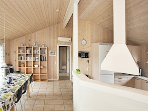 A compact kitchen with a Bosch refrigerator, wooden cabinets, and a tiled floor.