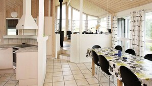 A modern kitchen with a central island, a dining area with a table and chairs, and large windows allowing natural light.