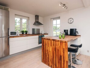 A modern kitchen with a wooden island, stainless steel appliances, and a large window providing natural light.