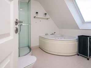 A modern bathroom with a glass shower enclosure, a freestanding bathtub, and a toilet.