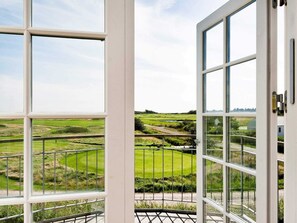 A view through a large window with a metal railing, overlooking a green landscape with fields and a road. - 5 Star Holiday Home in Romo (Rømø)