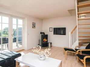 A modern living room with a fireplace, a TV mounted on the wall, and a staircase leading to an upper level.