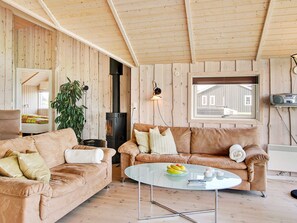 A cozy living room with a sofa, a glass coffee table, a fireplace, and a window with a view. - 5 Star Holiday Home in Storvorde (Storvorde)