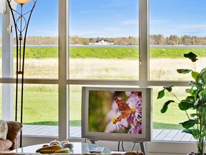 A room with a large window overlooking a grassy field and a house.