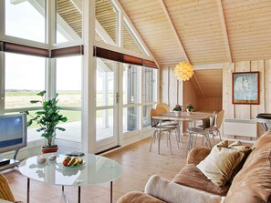 A spacious living area with a large glass door leading to an outdoor deck, a round glass table, and a cozy seating arrangement. - 5 Star Holiday Home in Storvorde (Storvorde)