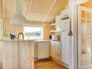 A compact kitchen with wooden walls, a window, and a microwave. - 5 Star Holiday Home in Storvorde (Storvorde)