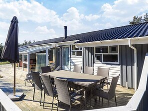 A covered outdoor patio with a table and chairs, a chimney, and a view of the house. - 4 Star Holiday Home in Albaek (Aalbaek)