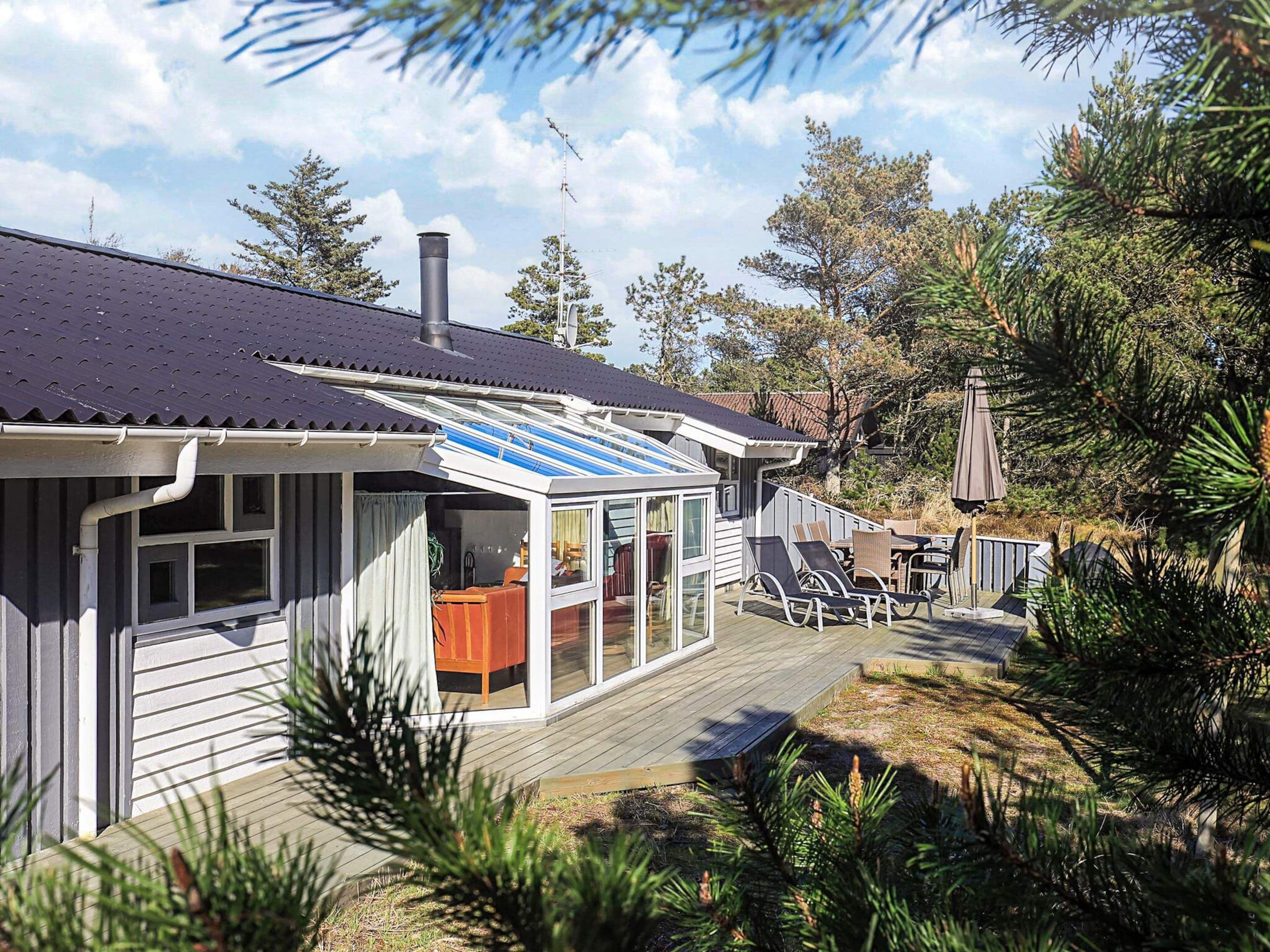 Une maison moderne dotée d’une terrasse, d’un patio couvert et d’une grande fenêtre.