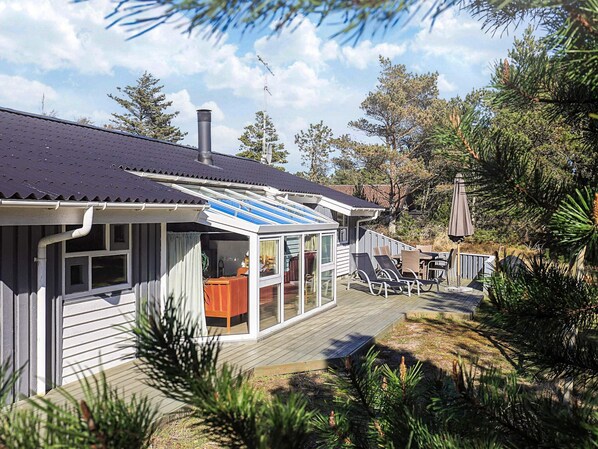 A modern house with a deck, a covered patio, and a large window.