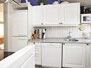 A kitchen with white cabinets, a microwave, a coffee maker, and a dishwasher.