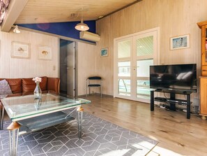 Ein Wohnzimmer mit einem Glastisch, einer Couch, einem Fernseher und einer Tür zum Pool.