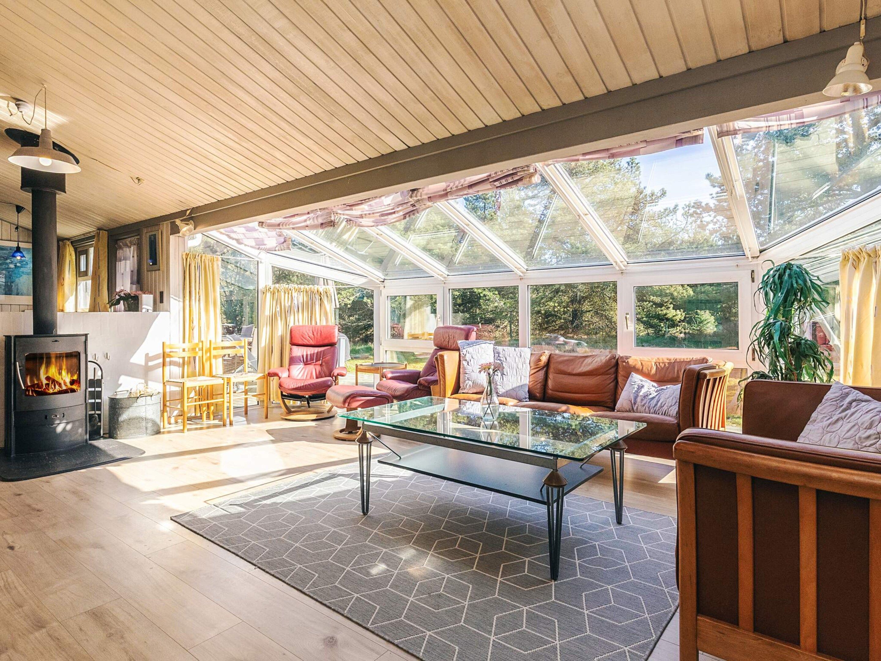 A spacious living area with a glass ceiling, leather furniture, and a fireplace.