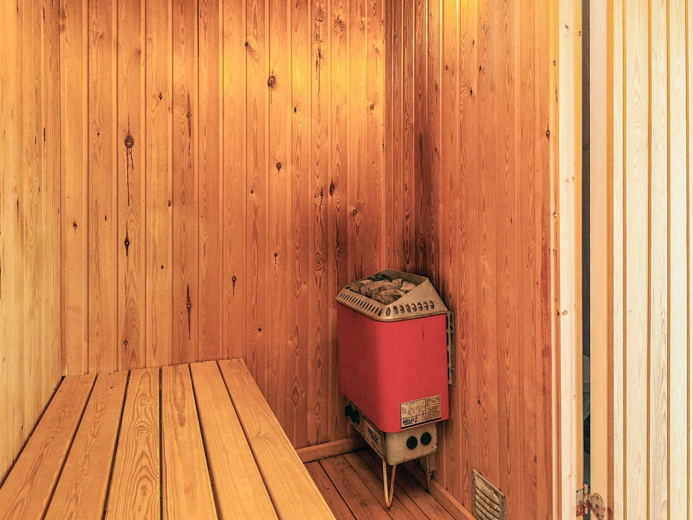 Una habitación de madera con un calentador rojo y una mesa de madera.