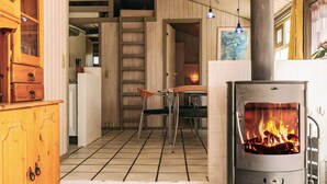 Un interior acogedor con chimenea de leña, mobiliario de madera y suelo de baldosas.