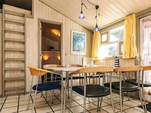 Ein Essbereich mit einem Holztisch, Stühlen, einer Leiter und einem Fenster mit Vorhängen.
