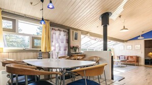 Un comedor con una mesa redonda, sillas y vistas al exterior a través de amplios ventanales.