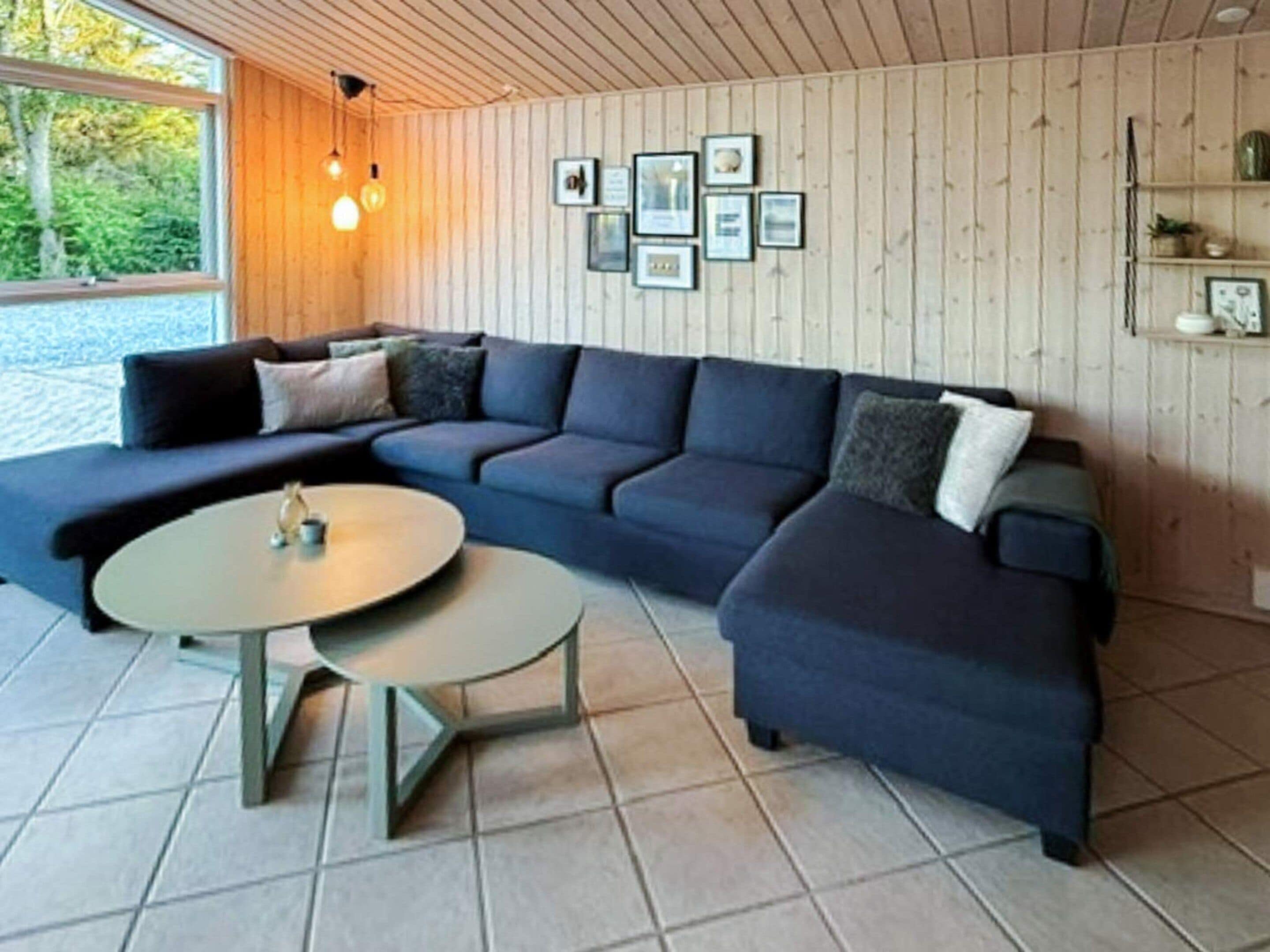 A modern living room with a sectional sofa, a round coffee table, and a wooden ceiling.