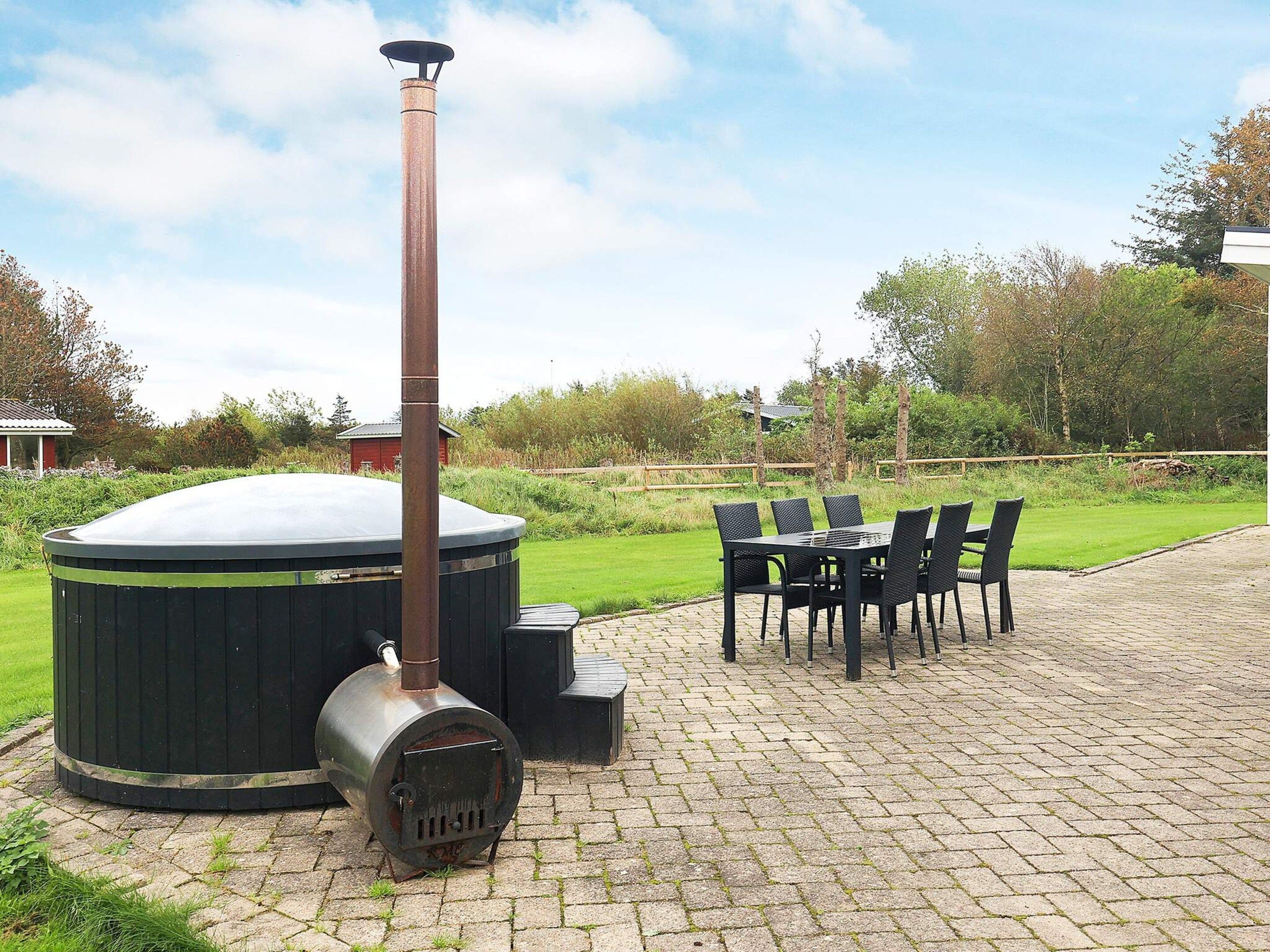 A hot tub with a chimney, surrounded by a brick patio and outdoor furniture.