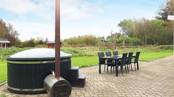 A hot tub with a chimney, surrounded by a brick patio and outdoor furniture.