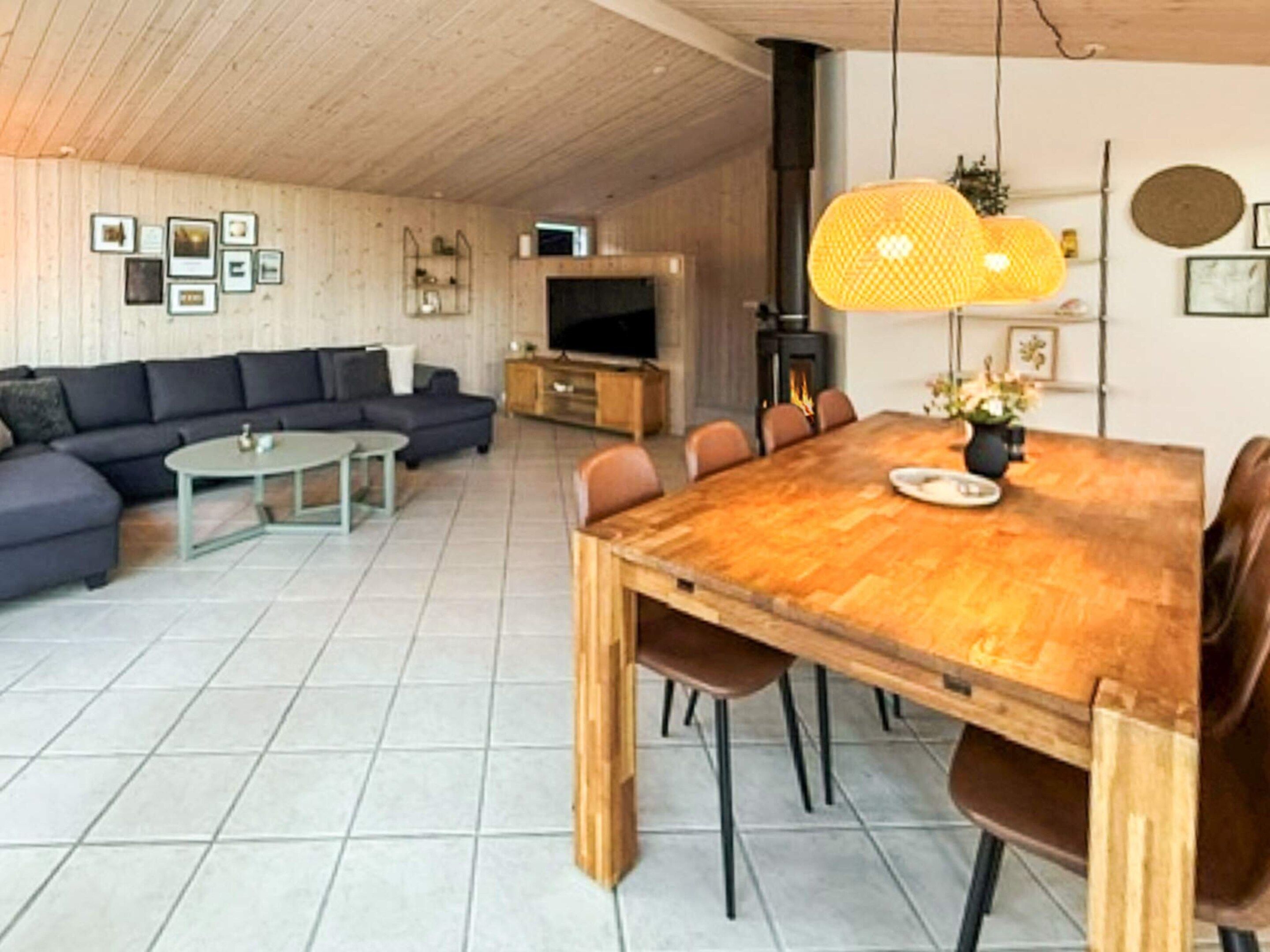 Un salon moderne avec une table à manger en bois, un canapé et un téléviseur.