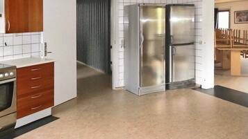 Eine Küche mit einem Edelstahl-Kühlschrank, Holzschränken und einer gefliesten Spritzschutzwand.