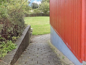 A paved pathway leading to a red building with a grassy yard. - 30 Person Holiday Home in Nordborg (Nordborg)