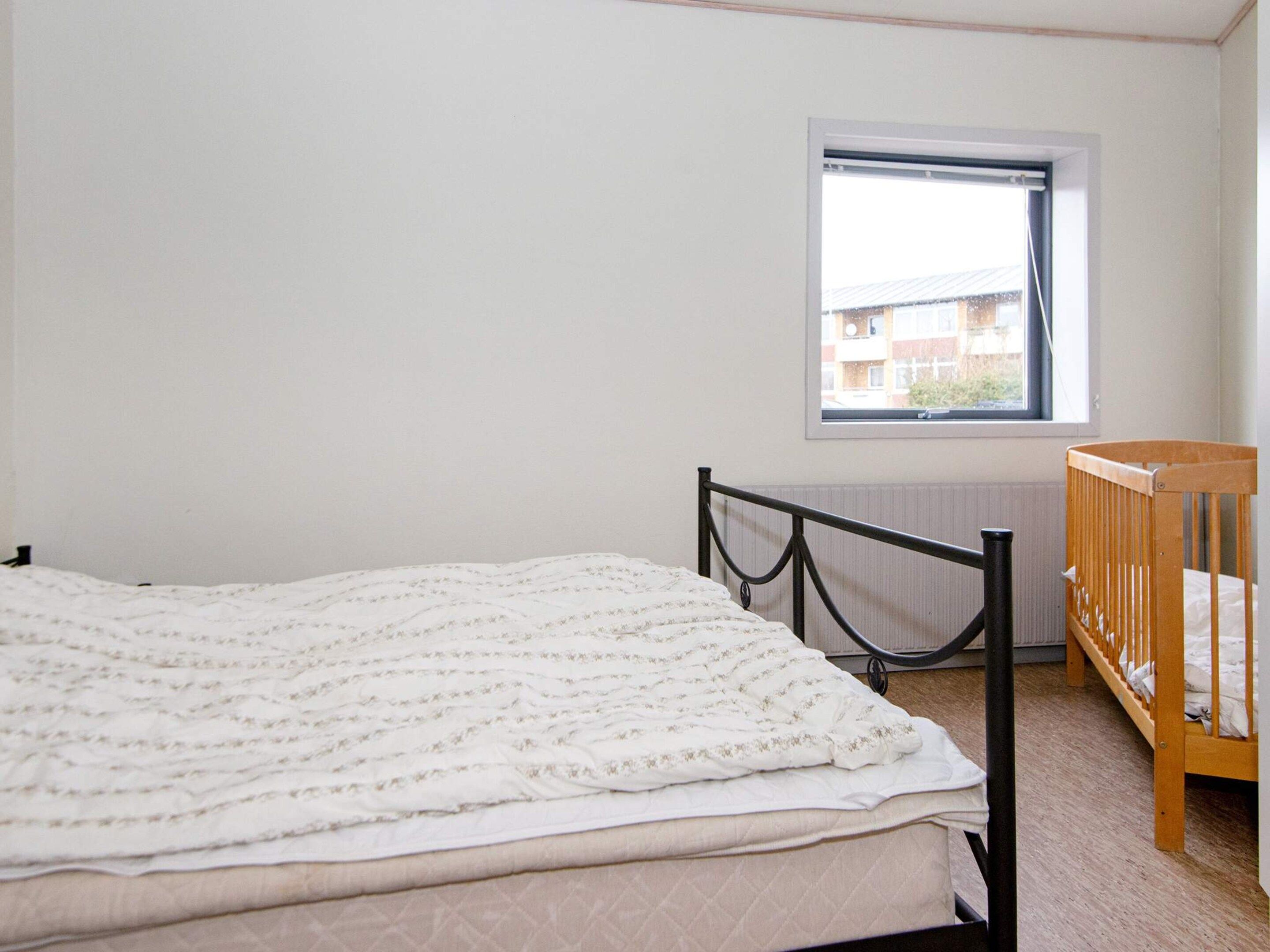 A bedroom with a bed, a crib, a window, and a radiator.