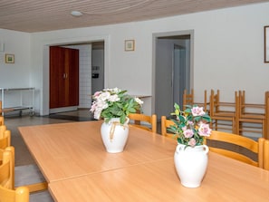A dining area with a wooden table, two white vases with flowers, and wooden chairs. - 30 Person Holiday Home in Nordborg (Nordborg)