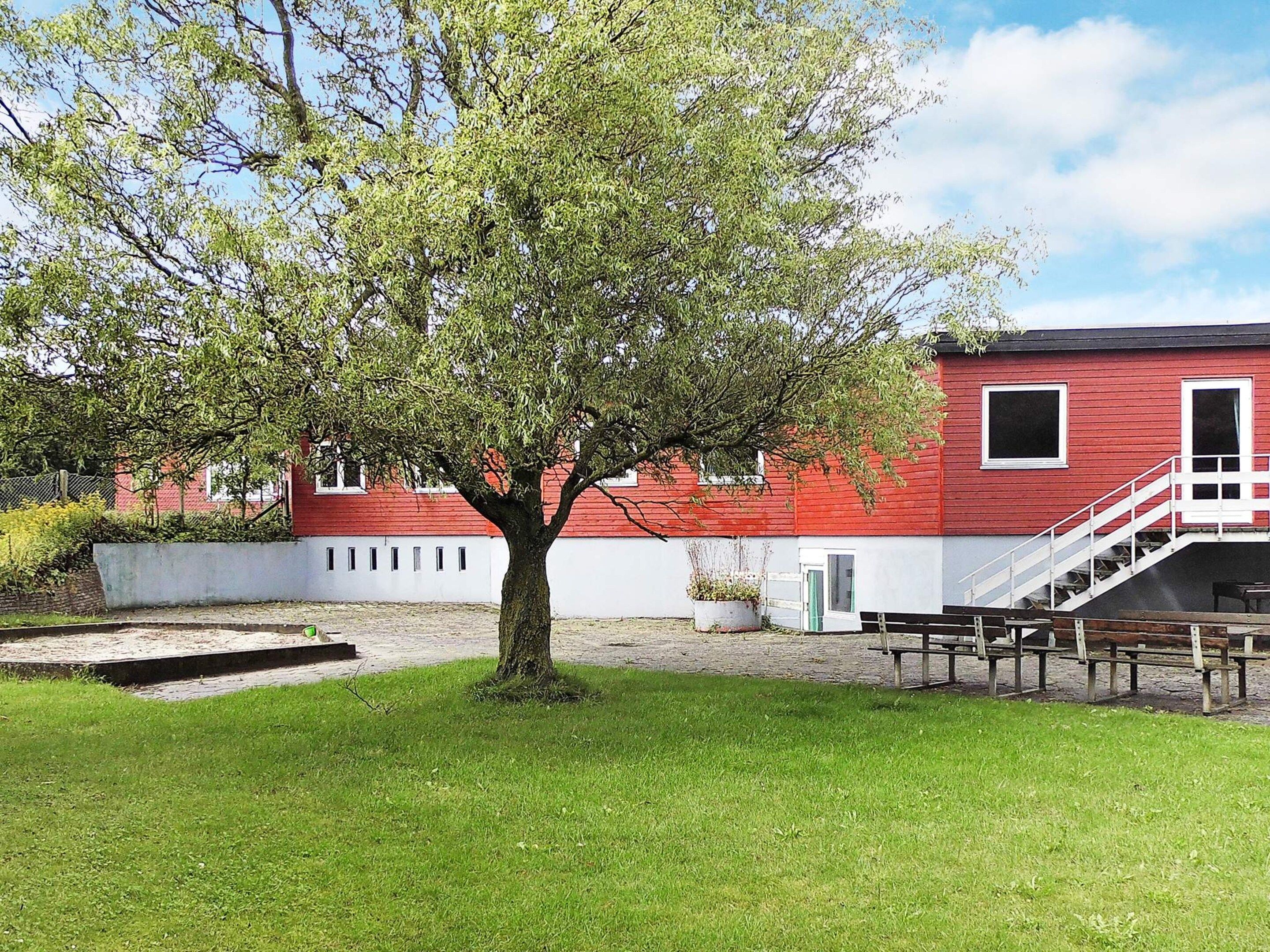 Ein rotes Gebäude mit einer weißen Treppe und einem Baum davor.