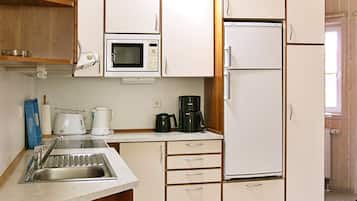 Cocina compacta con microondas, cafetera y refrigerador.