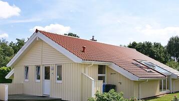 En etagers bygning med saddeltag, en veranda og en lille tilhørende garage.