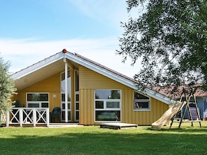 En gul bygning med saddeltag, store vinduer og en rutchebane i gården.
