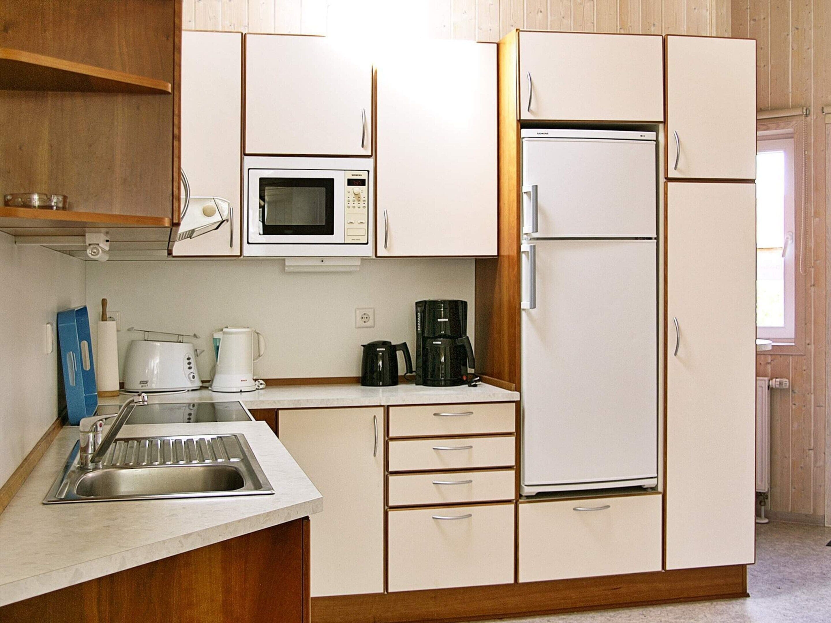 A compact kitchen with a microwave, coffee maker, and a refrigerator.