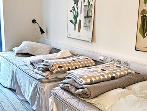 A bedroom with two beds, a bedside lamp, and botanical illustrations on the wall. - Holiday Home in TvÃ¥Ã¥ker (Tvaaker)