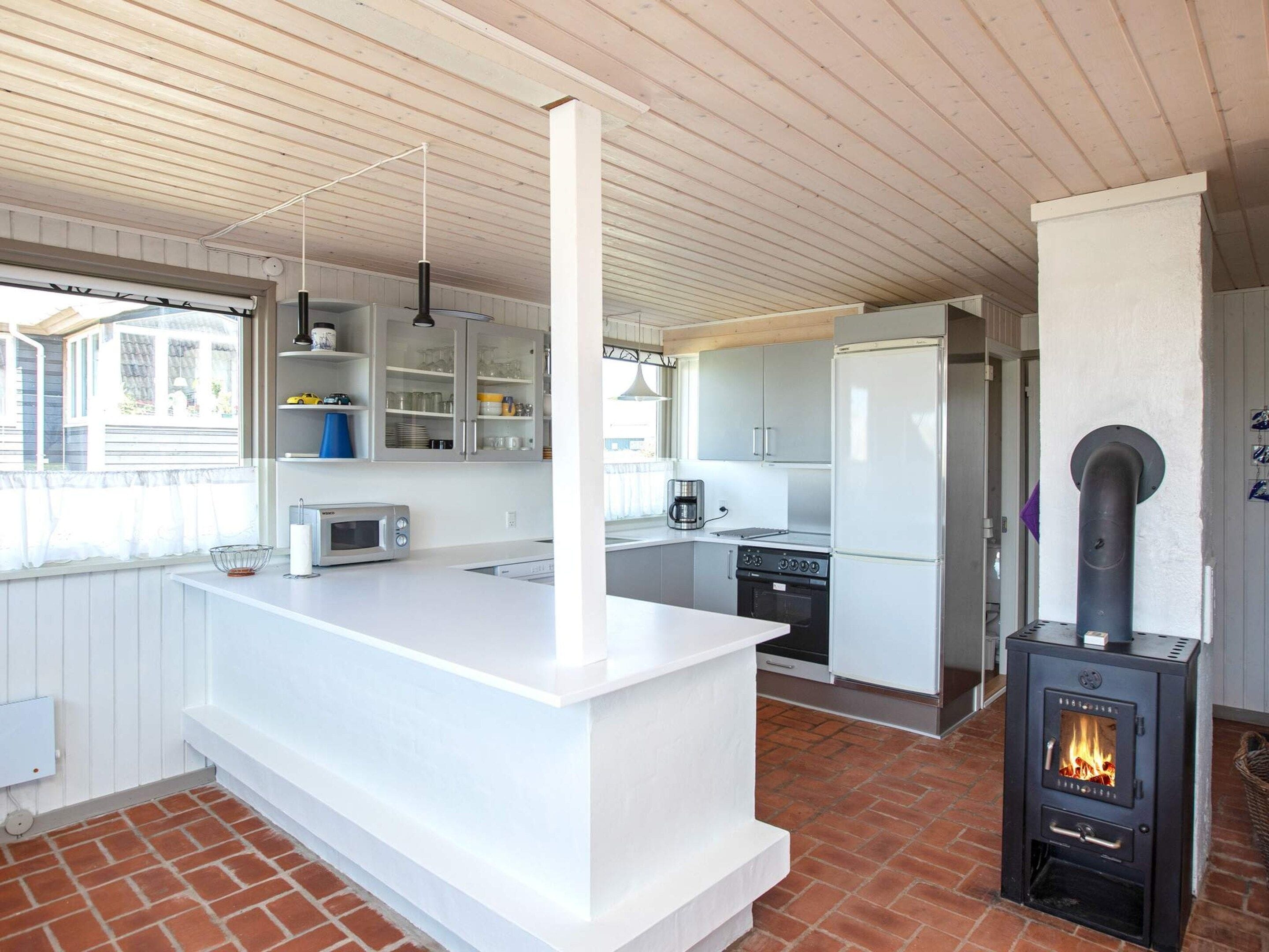 A modern kitchen with a central island, built-in appliances, and a wood-burning stove.