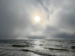 A cloudy sky over the ocean with sunlight breaking through.