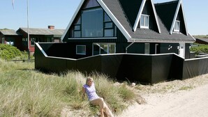 A modern house with a unique angular design, large windows, and a sandy surrounding. - 4 Star Holiday Home in Blokhus (Blokhus)