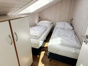 A dorm-style room with two single beds, a wardrobe, and a skylight. - Holiday Home in Otterndorf (Otterndorf)