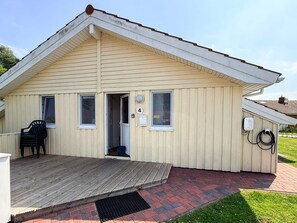 A small, single-story building with a wooden deck and a brick entrance. - Holiday Home in Otterndorf (Otterndorf)