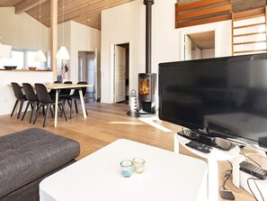 Un salon moderne doté d’un téléviseur à écran plat, d’une cheminée, d’un coin repas avec des chaises et d’un canapé.