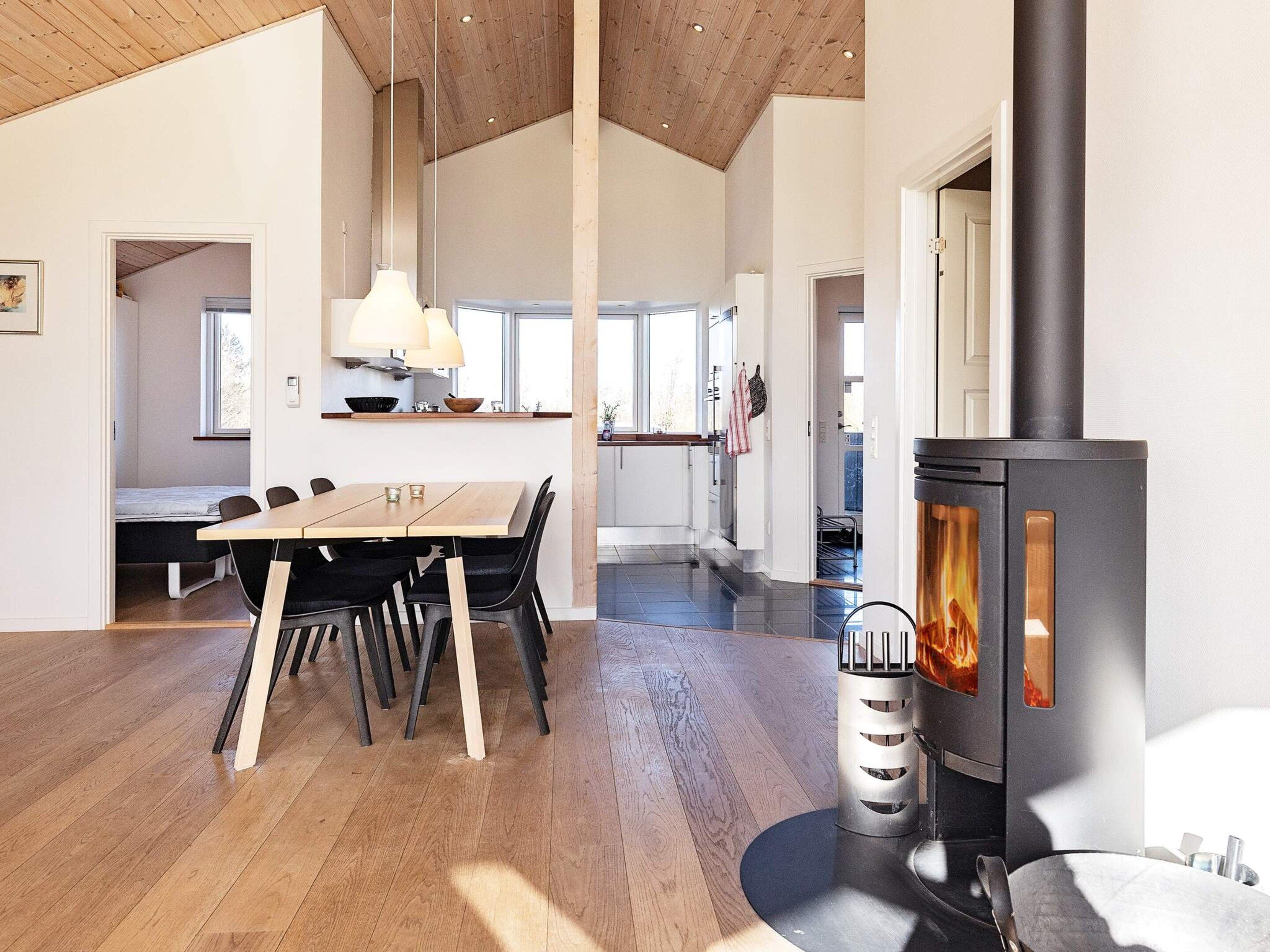 Un intérieur moderne comprenant un coin repas, une cuisine et un poêle à bois.