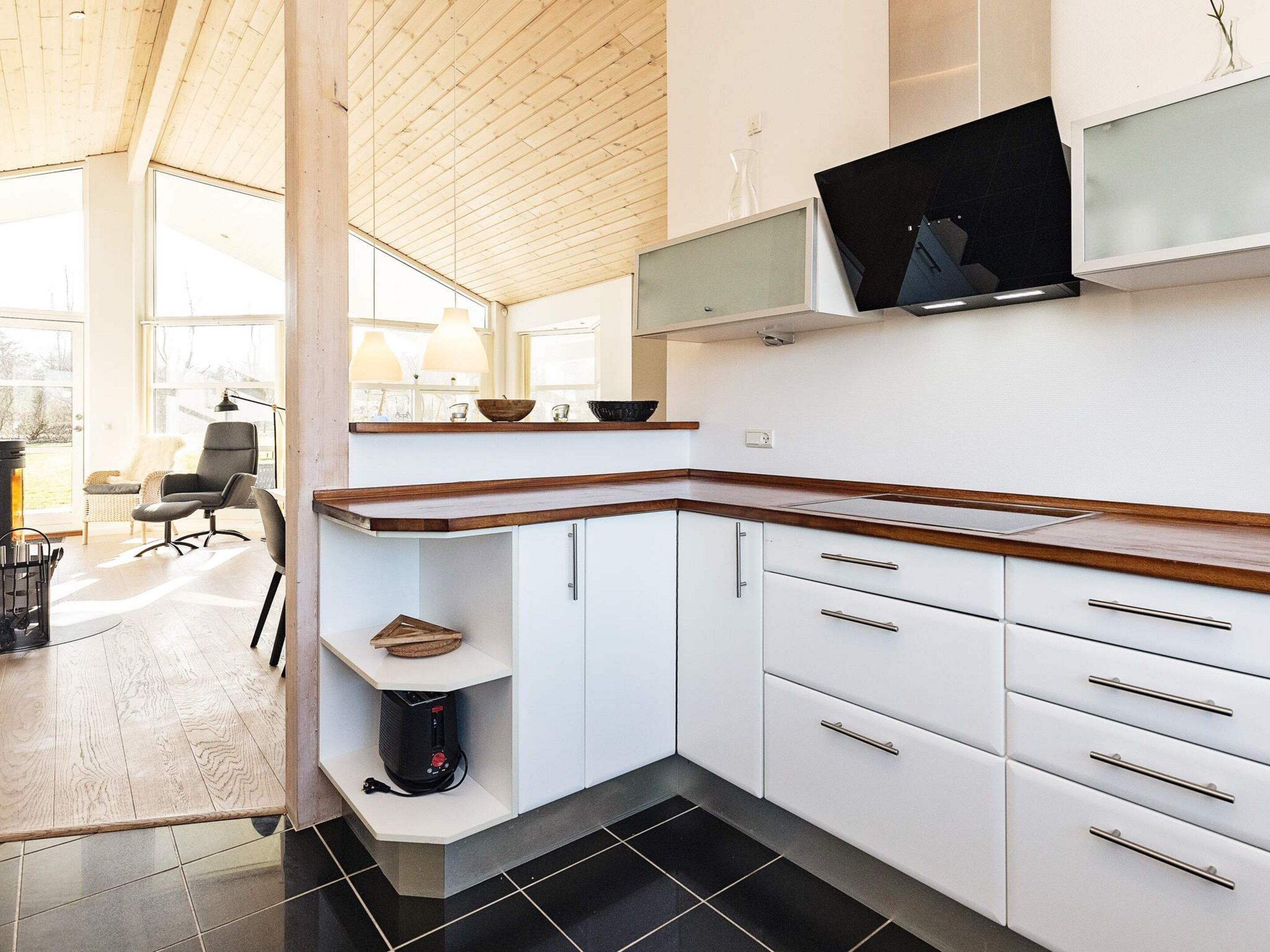 A modern kitchen with white cabinets, a wooden countertop, and a built-in TV.