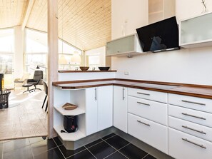 Une cuisine moderne avec des armoires blanches, un plan de travail en bois et un téléviseur encastré.