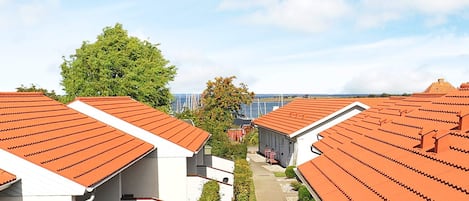 En række moderne bygninger med røde tegltage og hvide vægge, anlagt i en lige linje med en sti imellem.