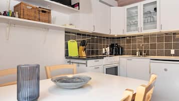 A modern kitchen with white cabinets, a black countertop, and a tiled backsplash.