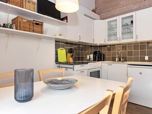 A modern kitchen with white cabinets, a black countertop, and a tiled backsplash. - 4 Person Holiday Home in Aeroskobing (Aeroskobing)