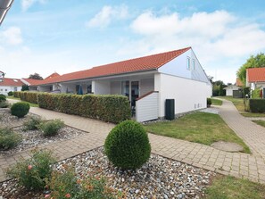 A modern residential building with a red-tiled roof, a covered porch, and a well-maintained garden with a gravel pathway. - 4 Person Holiday Home in Aeroskobing (Aeroskobing)
